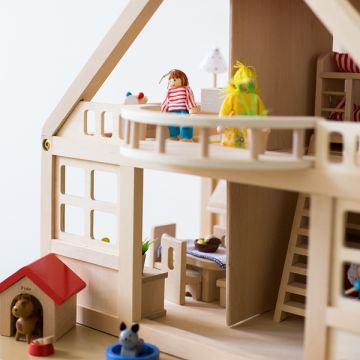 in einem hölzernen Puppenhaus stehen eine kindliche und eine jugendliche Puppe