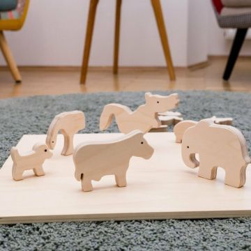 Systemische Tierfiguren aus Holz stehen auf einem Holzbrett