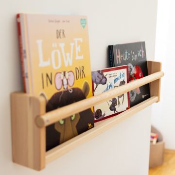 drei liebevoll illustrierte Kinderbücher stehen auf einem Wandregal