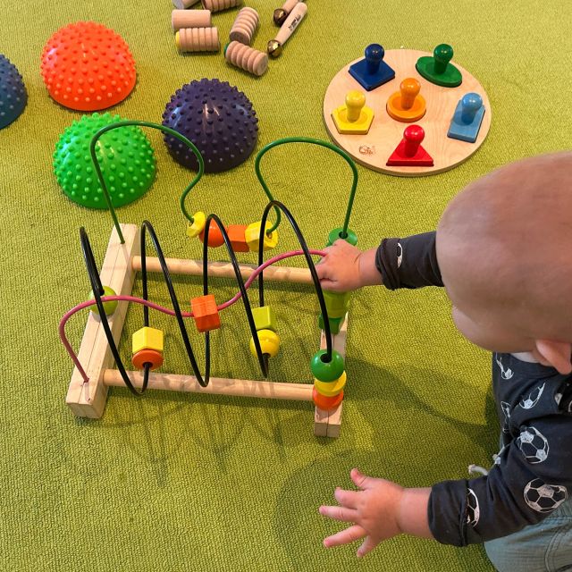 Baby spielt mit einem Geschicklichkeitsspiel in der Mama-Baby-Spielgruppe
